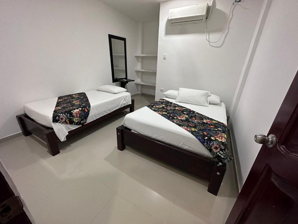 Habitación con 2 camas y espejo. en Hotel Casa Evan en Mompox