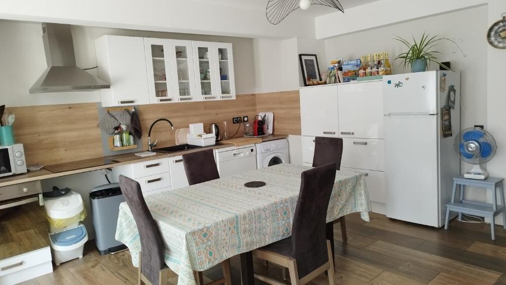 a kitchen with a table and a white refrigerator at Ruthene Etape Appartement T3 in Rodez