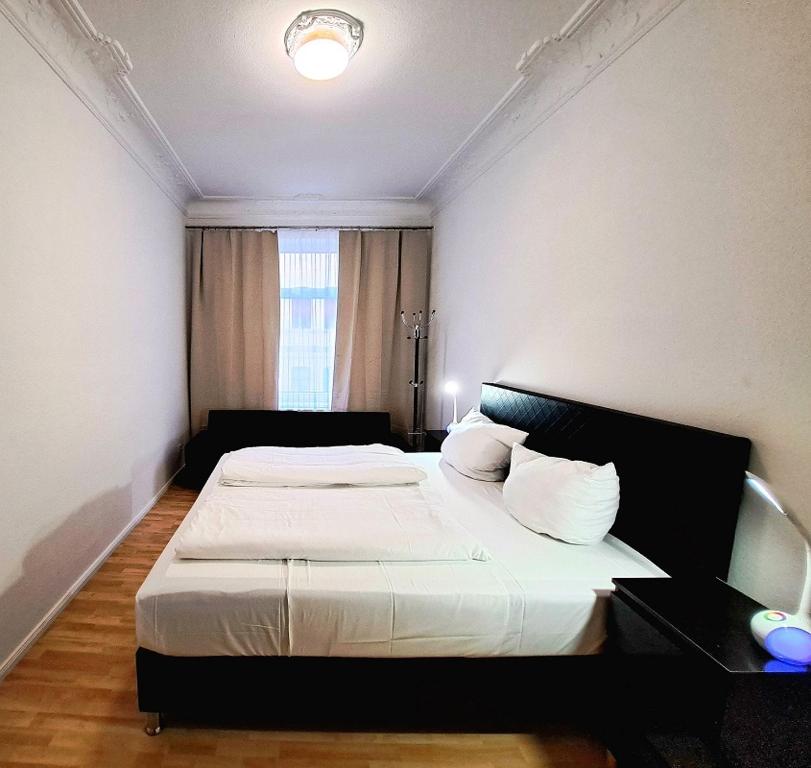 ein Schlafzimmer mit einem großen Bett mit weißer Bettwäsche und einem Fenster in der Unterkunft Apartment Hotel Adler Leipzig in Leipzig