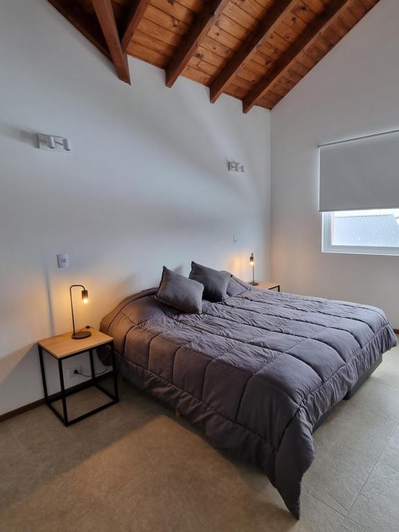 ein Schlafzimmer mit einem großen Bett und einem Tisch in der Unterkunft Villa Maihue departamentos de montaña - Caviahue in Caviahue