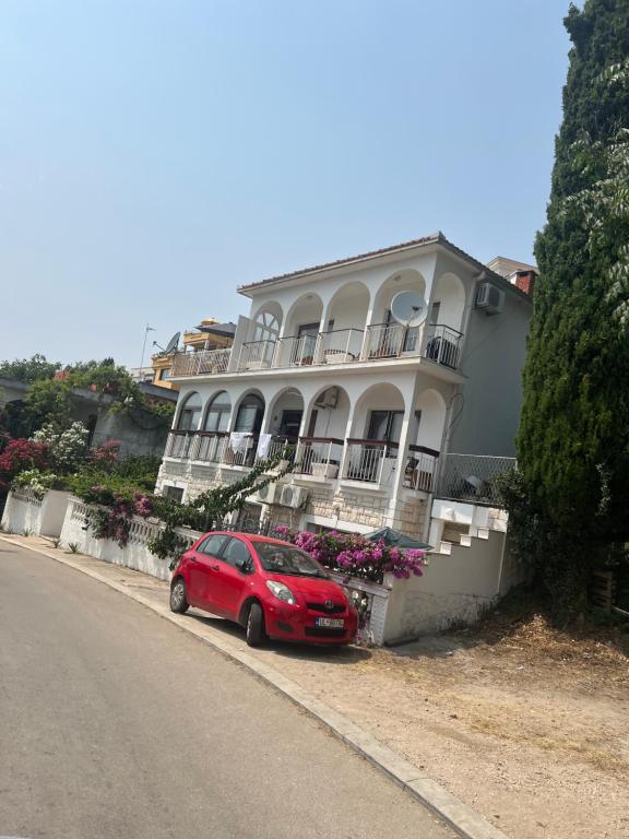 ein rotes Auto, das vor einem Haus parkt in der Unterkunft Apartment Salaj in Ulcinj