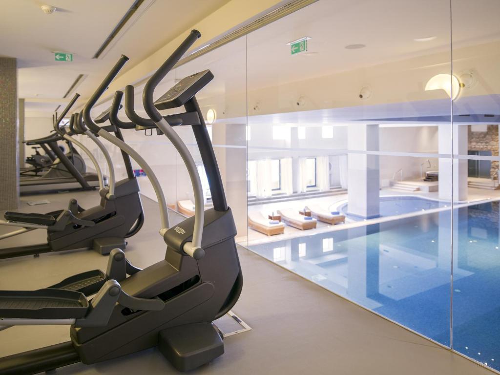 a gym with cardio machines and a swimming pool at Hotel Excelsior in Dubrovnik