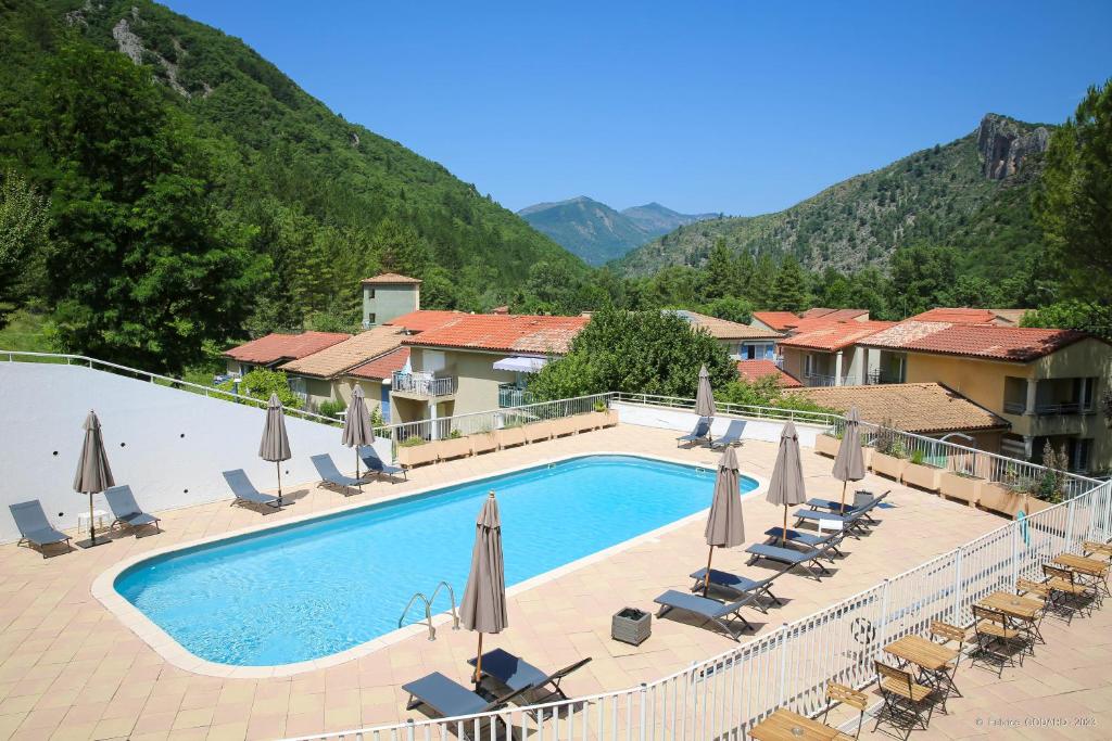 a hotel with a swimming pool with chairs and umbrellas at Hôtel Le Refuge des Sources in Digne-les-Bains