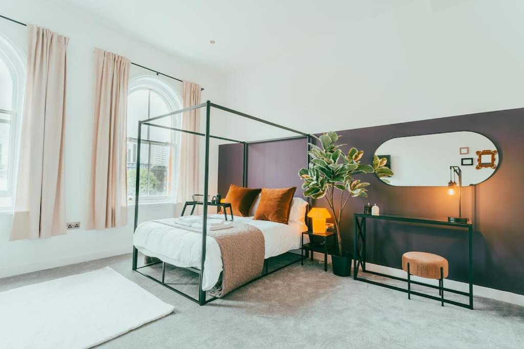 ein Schlafzimmer mit einem Himmelbett und einem Spiegel in der Unterkunft Dusk House - Wyndale Living - B'ham JQ Townhouse in Birmingham
