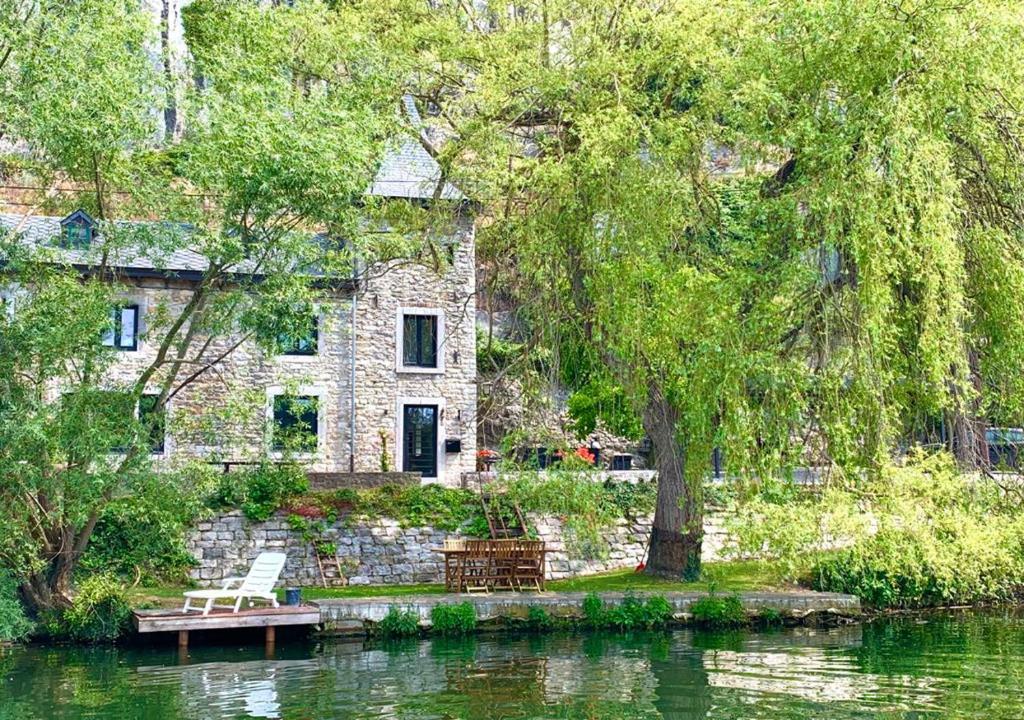 a stone house sitting on the side of a lake at Pieds dans l'eau Private Wellness Bordure de Meuse in Lustin