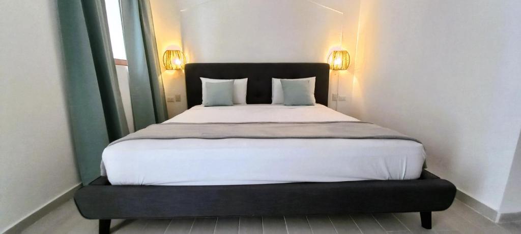 a bed with white sheets and pillows in a room at La Piazzetta Suites Punta Cana Beach - Los Corales Village in Punta Cana