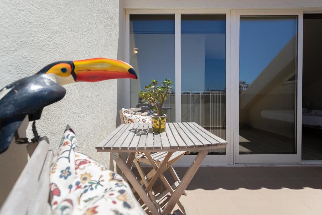 a toucan sitting on a bench next to a table at BeGuest Parede Beach Apartment – Cascais in Parede