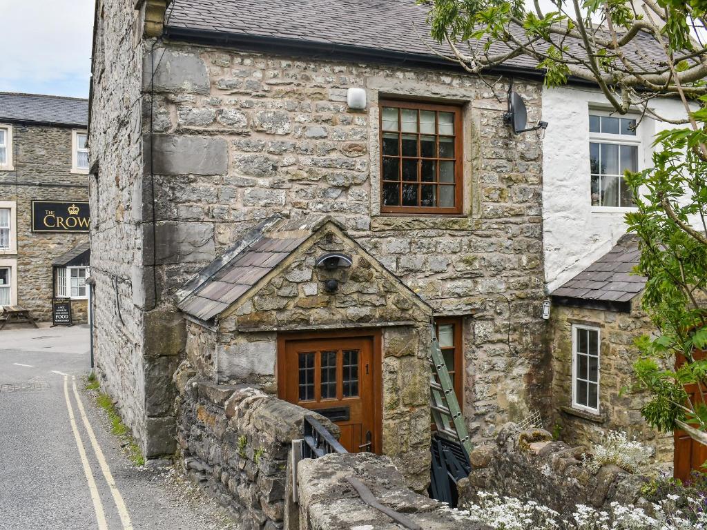 un antiguo edificio de piedra con puerta de madera en Three Peak Cottage, en Horton in Ribblesdale