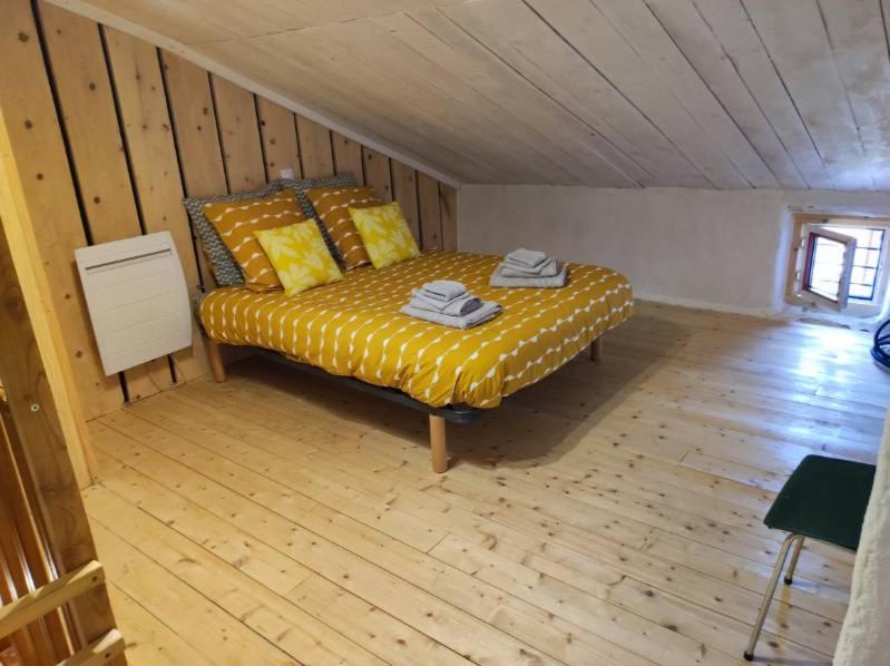 1 dormitorio con 1 cama en una habitación con suelo de madera en maison de vigneron en Mareugheol