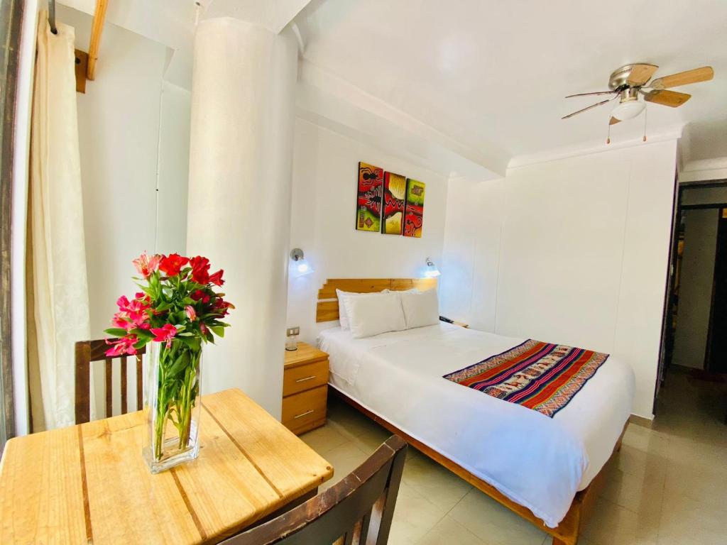 a bedroom with a bed and a vase of flowers on a table at Vista Machu Picchu in Machu Picchu