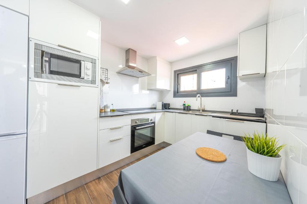 cocina con armarios blancos y mesa en ApartamentosDnord en Reus