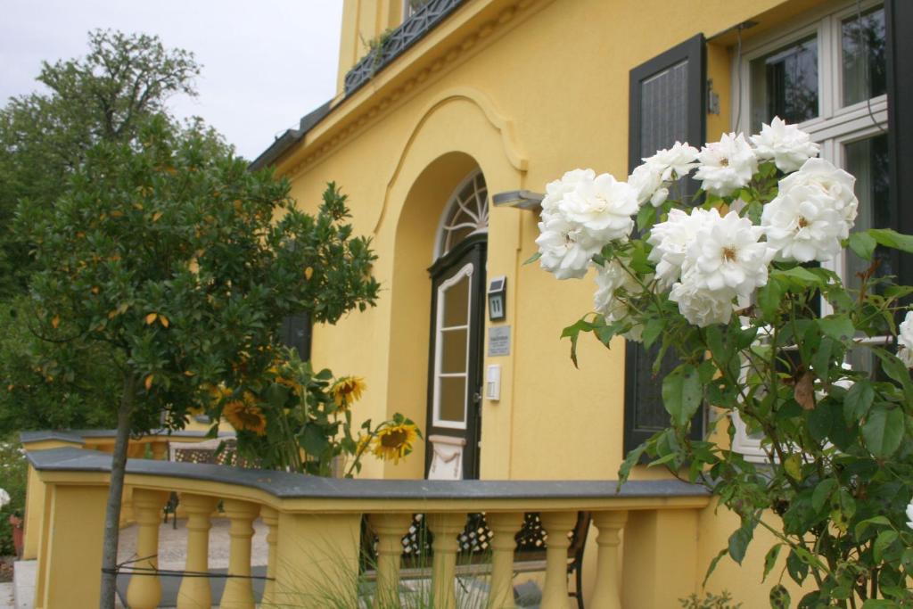 a yellow house with a balcony with white flowers at Gutshaus mit Seeblick - ökologisch & nachhaltig in Lübow