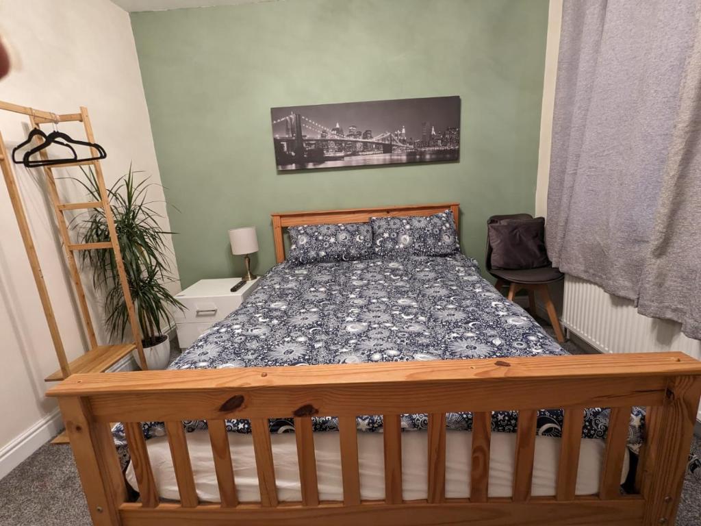 ein Schlafzimmer mit einem Bett mit einem Bettrahmen aus Holz in der Unterkunft Large Cosy Room to Stay in South Reading in Shinfield