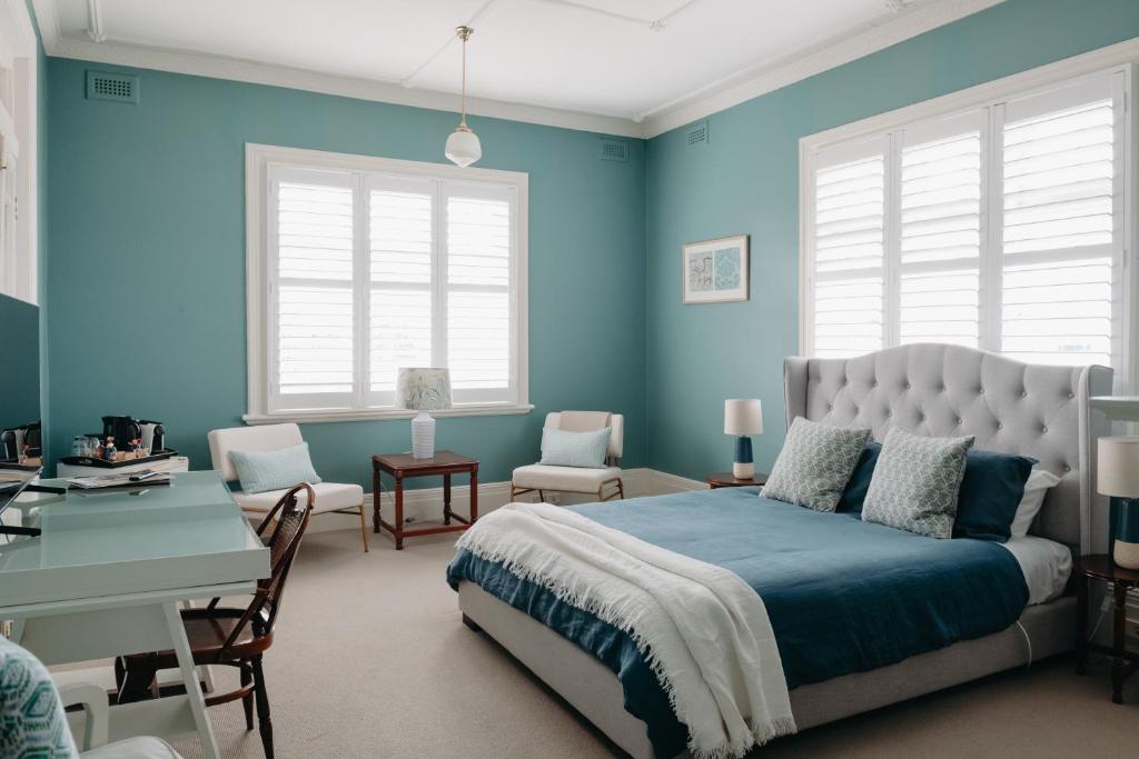1 dormitorio con paredes azules, 1 cama y escritorio en The Westbury Dubbo, en Dubbo