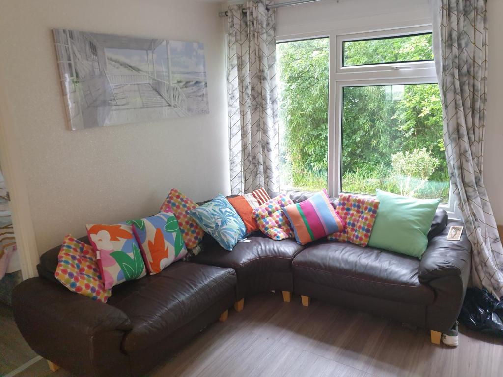 een woonkamer met een leren bank en een raam bij Wood View - Penstowe Park in Kilkhampton