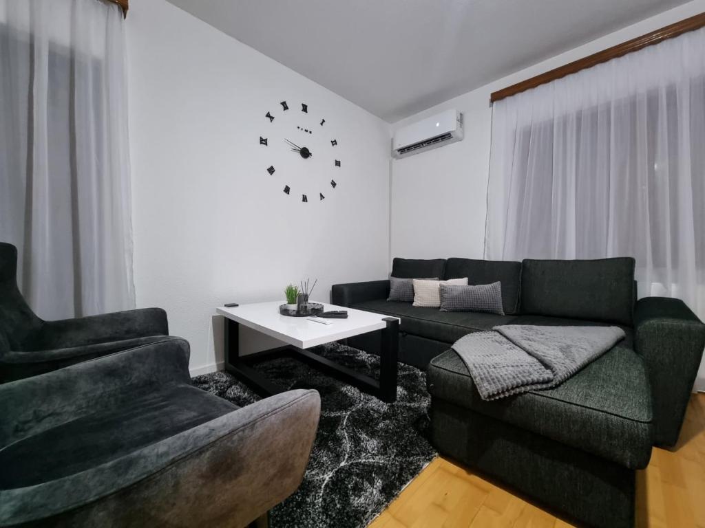 a living room with a couch and chairs and a clock at GOLD Apartman in Sanski most