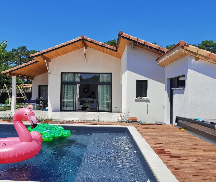 une maison avec une piscine et un flamingo rose dans l'établissement Villa des Oyats, à Vieux-Boucau-les-Bains