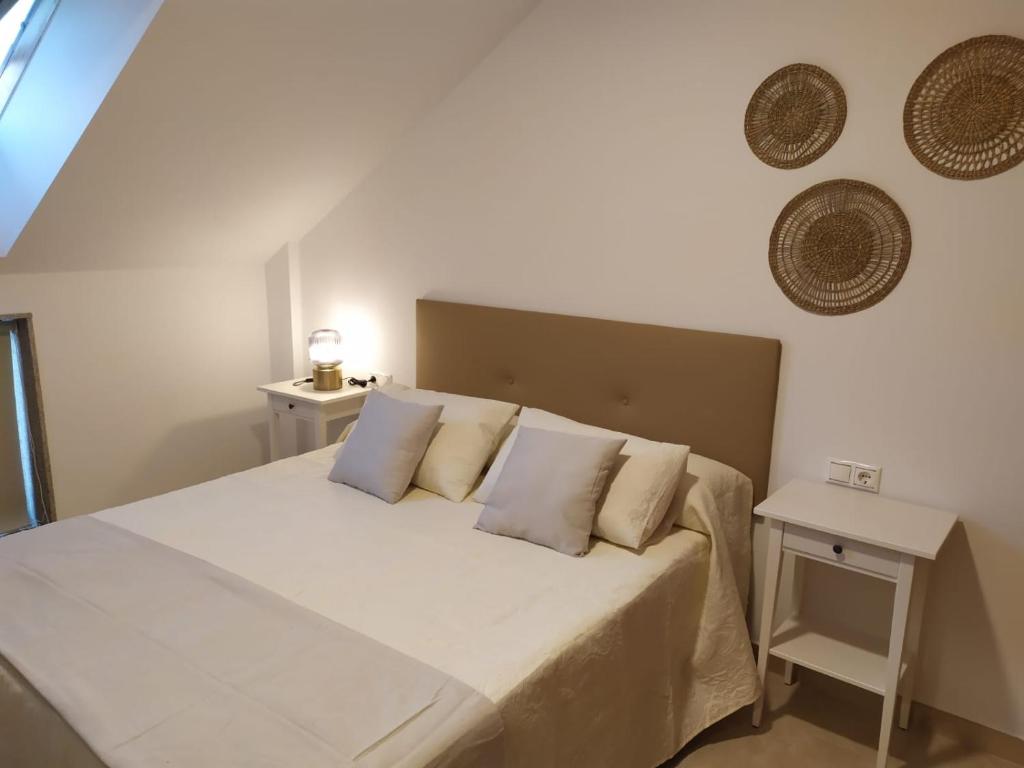 1 dormitorio con 1 cama grande con sábanas y almohadas blancas en ATICO A 3 KM DE SANXENXO CON PISCINA Y GARAJE en Sanxenxo