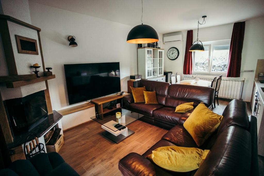 a living room with a leather couch and a flat screen tv at Vila Odmor 