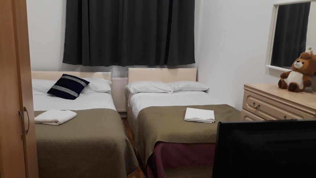 un pequeño dormitorio con 2 camas y un osito de peluche en 30 willesden lane, en Londres