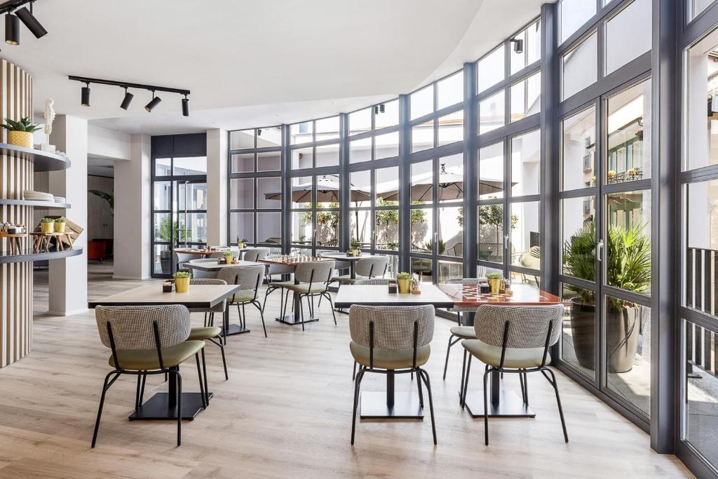 アスコナにあるLiving Ascona Boutique Hotel - Smart Hotelのテーブルと椅子、大きな窓のあるレストラン
