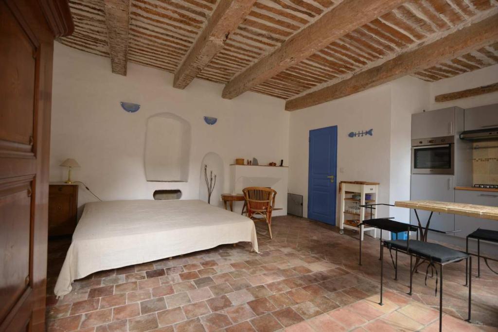 1 dormitorio con 1 cama blanca y cocina en Studio de la cheminée et studio de la place en Sigonce