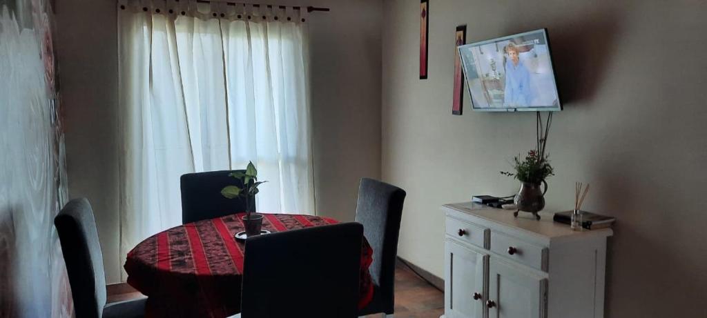 comedor con mesa, sillas y TV en Alojamiento Casa en Pilar en Pilar