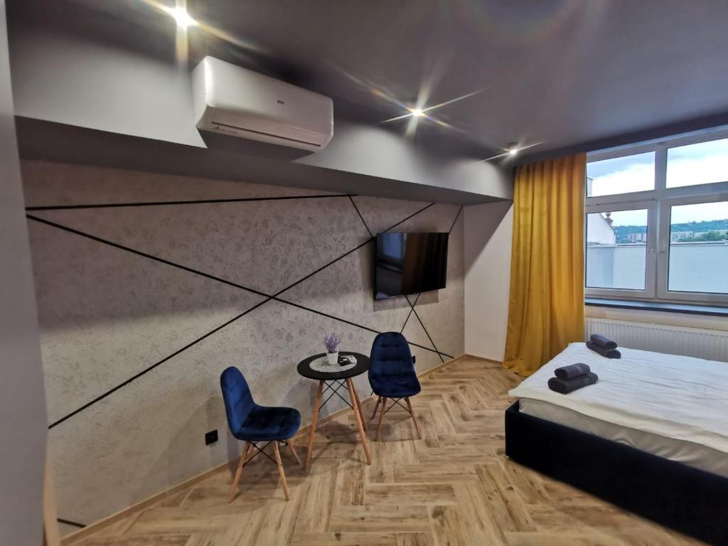 sypialnia z łóżkiem, stołem i 2 niebieskimi krzesłami w obiekcie LOFT HOUSE APARTMENTS w mieście Przemyśl