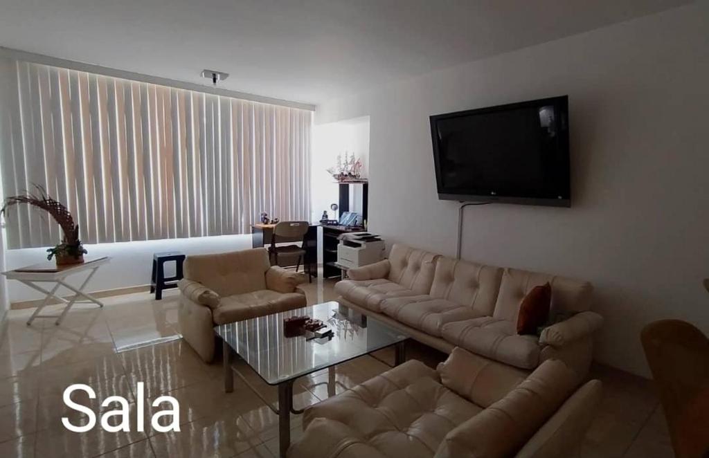 a living room with a couch and a tv at Contemporary in Caracas