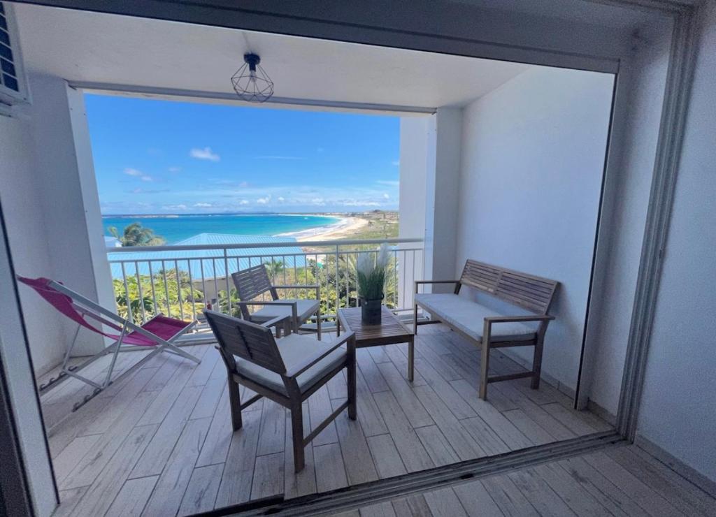 Un balcón con sillas y vistas al océano. en Studio Epoustouflante Vue Mer St Martin en Saint Martin