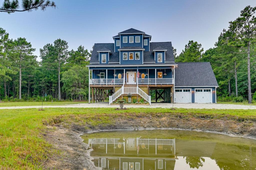 een groot blauw huis met een reflectie in een vijver bij Expansive Georgetown Home with Decks and Fire Pit! in Georgetown