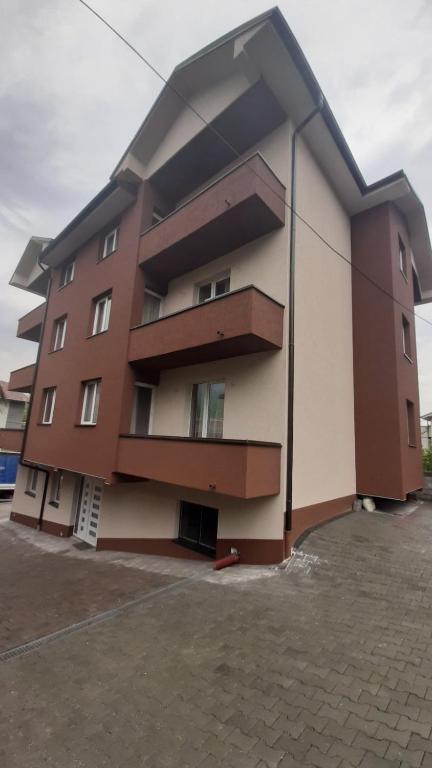 a brown and white building in a parking lot at Apartmani Milina in Lepterija