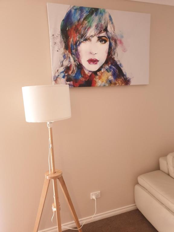 a painting of a woman on the wall next to a lamp at Ensuite room with Private Bath toilet CBD Airport in Werribee