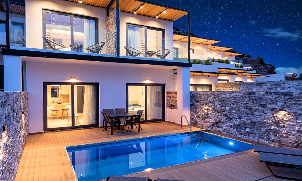 a villa with a swimming pool in front of a house at Aelia Suites in Agios Nikolaos