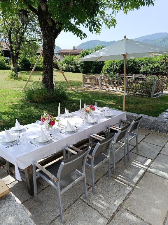 a long white table with chairs and an umbrella at Geigelstein Chalets in Unterwössen