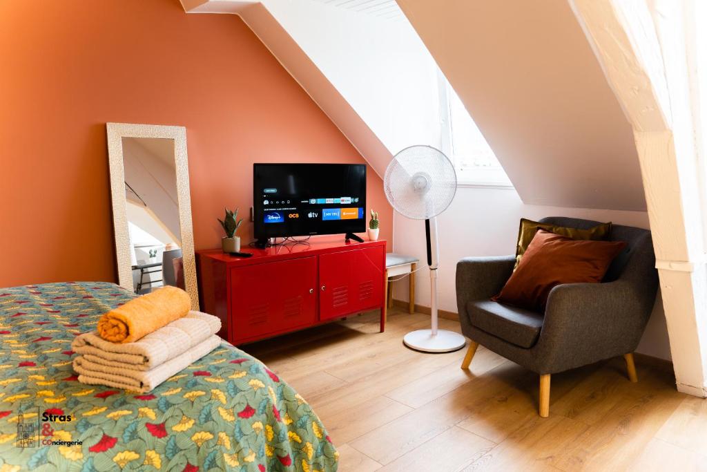 - une chambre avec un lit, une télévision et une chaise dans l'établissement Lyam, à Strasbourg