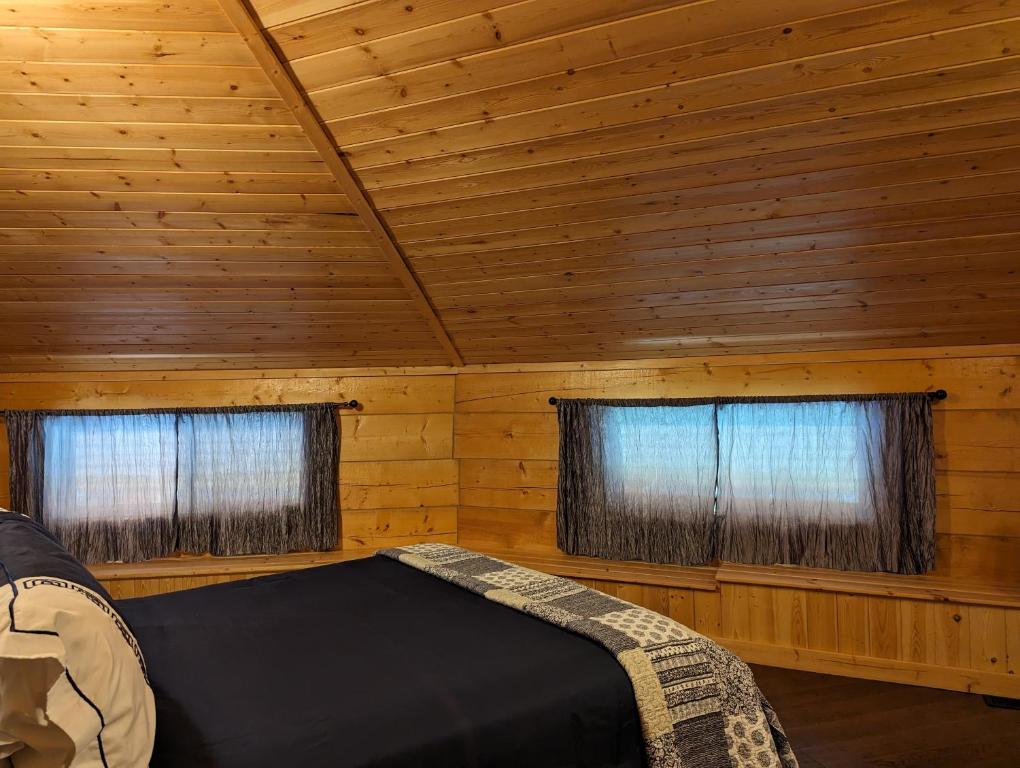 a bedroom with two windows in a log cabin at Sundance Country Lodge B&B in Marlboro