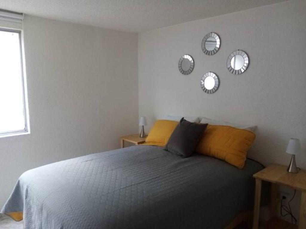1 dormitorio con 1 cama y reloj en la pared en LISBOA Hermoso departamento para 6 personas en cdmx, en Ciudad de México