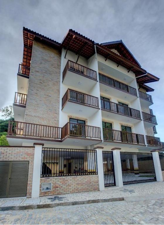 a tall white building with balconies on it at Apartamento Dei Fiori in Guaramiranga