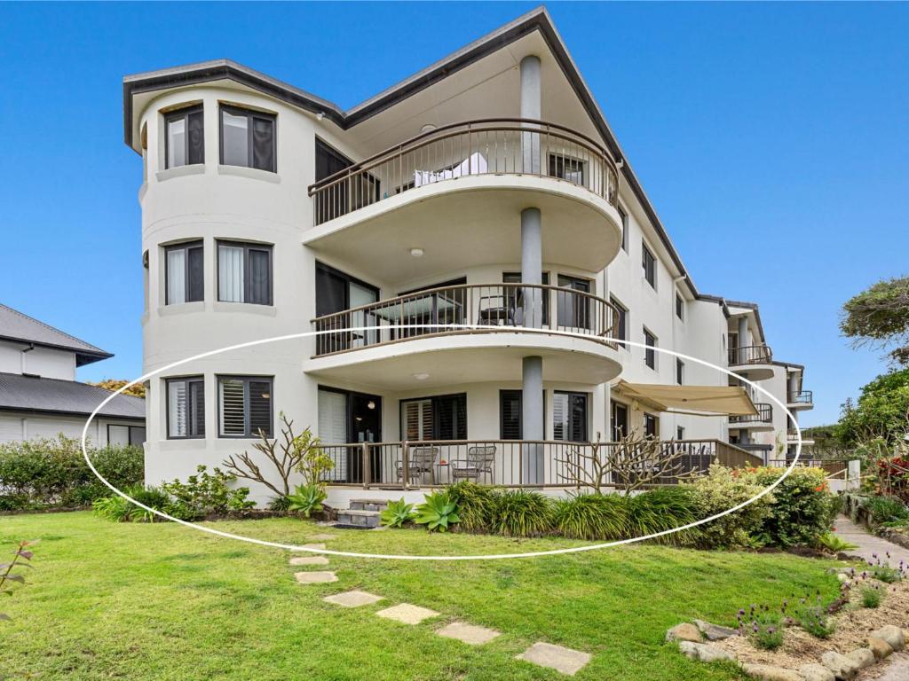 a large white house with a yard at Shoreline 3 Beachfront Apartment in Hastings Point