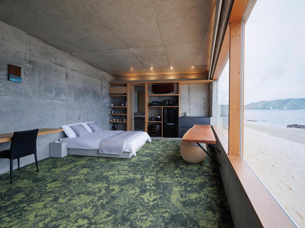 a bedroom with a bed and a view of the beach at Denpaku The Beachfront MIJORA in Amami