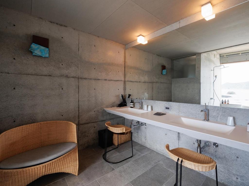 a bathroom with a sink and two chairs at Denpaku The Beachfront MIJORA in Amami