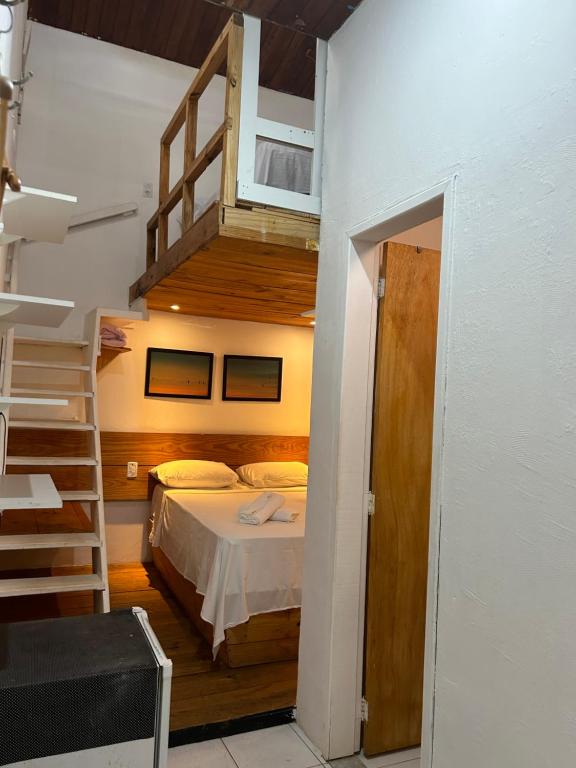 Un pequeño dormitorio con una cama y una escalera en Pousada Bar Café Algas Marinhas en Praia do Forte