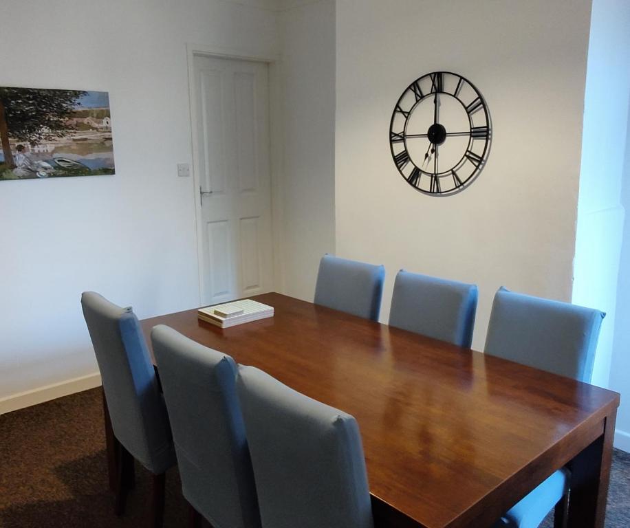 a dining room table with chairs and a clock on the wall at Leicester Street in Burton upon Trent