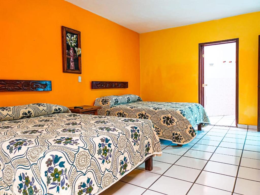 Hotel Jardín في Erongarícuaro: سريرين في غرفة بجدران برتقالية