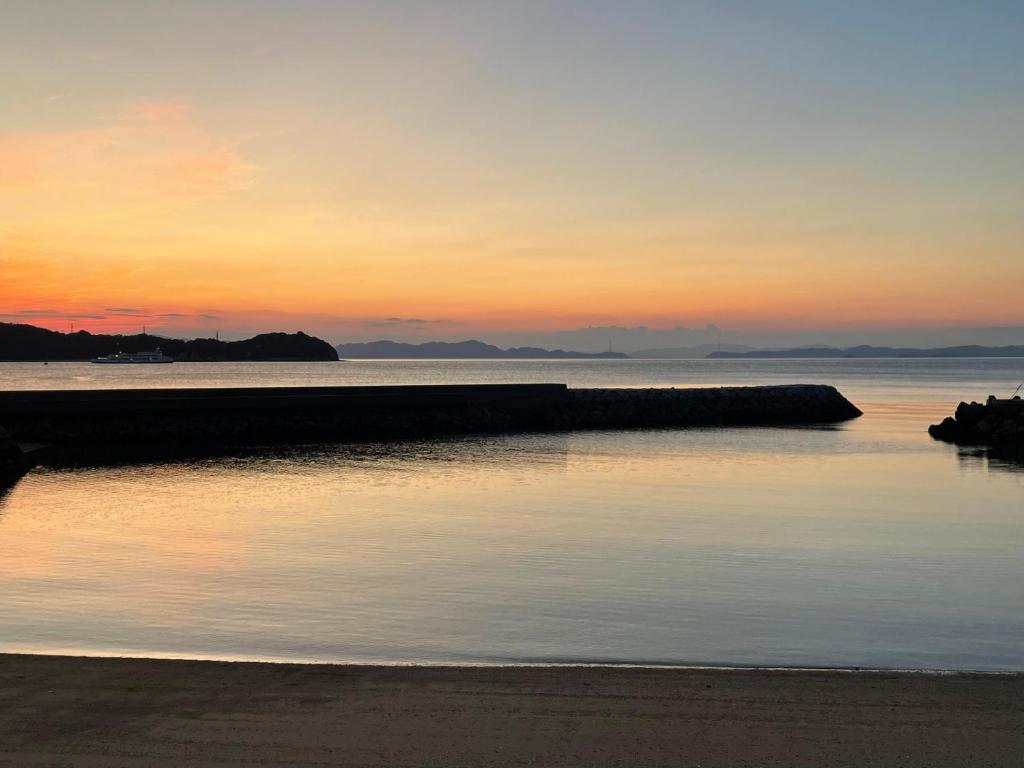 una puesta de sol sobre un cuerpo de agua con un muelle en SEA&SEE KOSE, en Kose