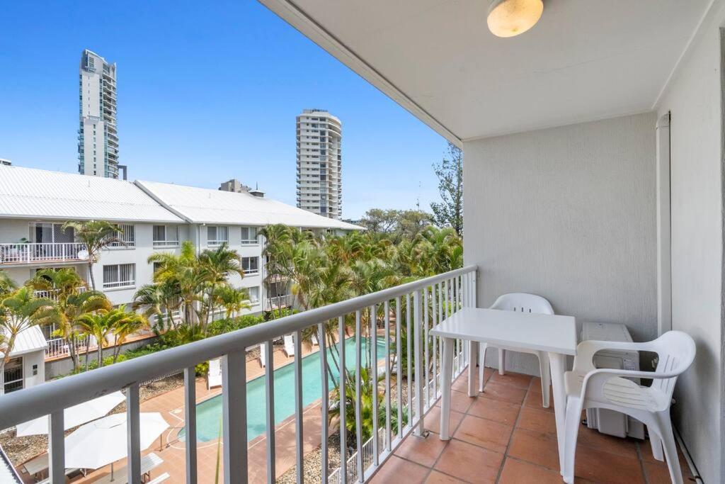 balcón con mesa, sillas y piscina en Bay Lodge - Private Apartments, en Gold Coast