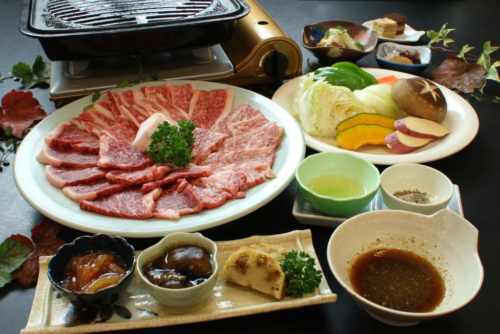 una mesa cubierta con platos de carne y tazones de comida en Daisen View Heights, en Daisen