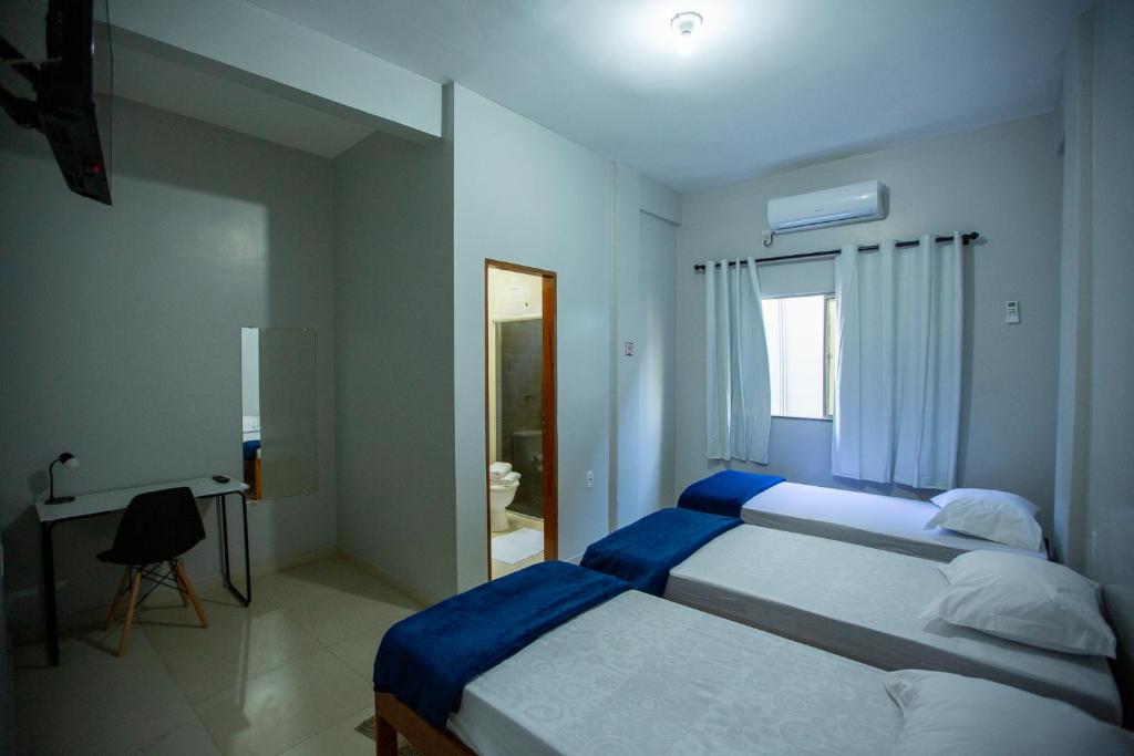 1 dormitorio con 2 camas, escritorio y espejo en Solare Hotel, en Barcarena
