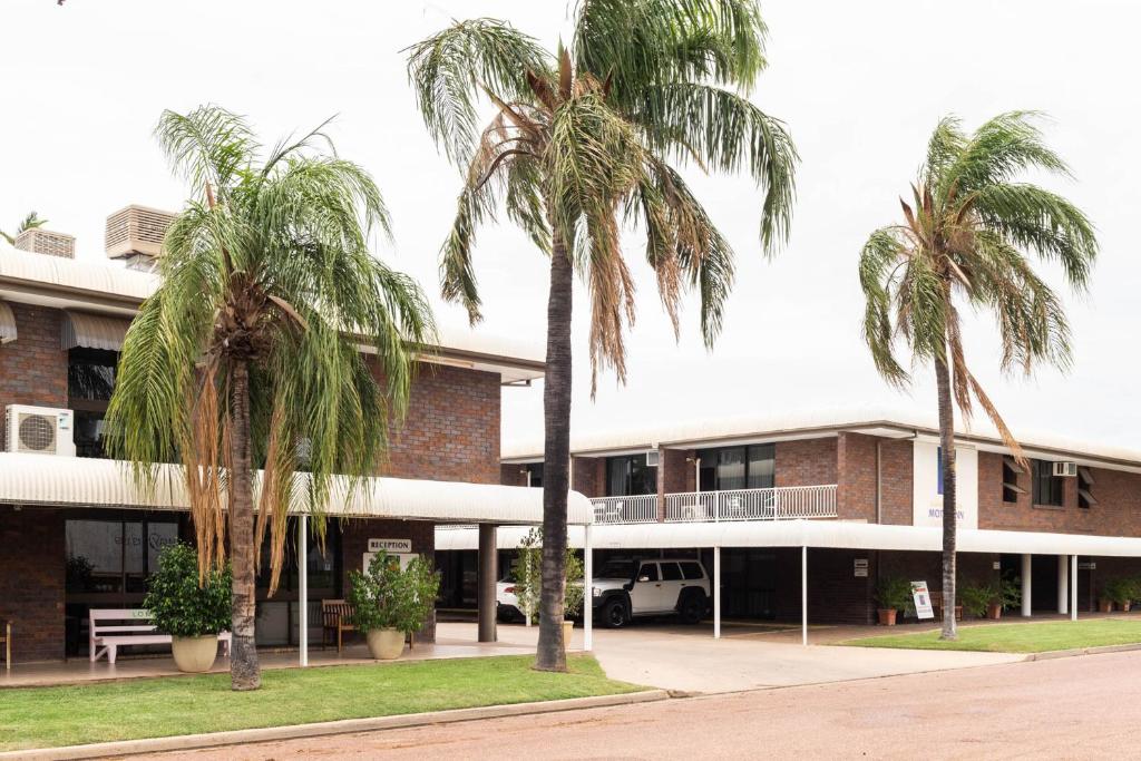 a building with palm trees in front of it at Longreach Motor Inn in Longreach